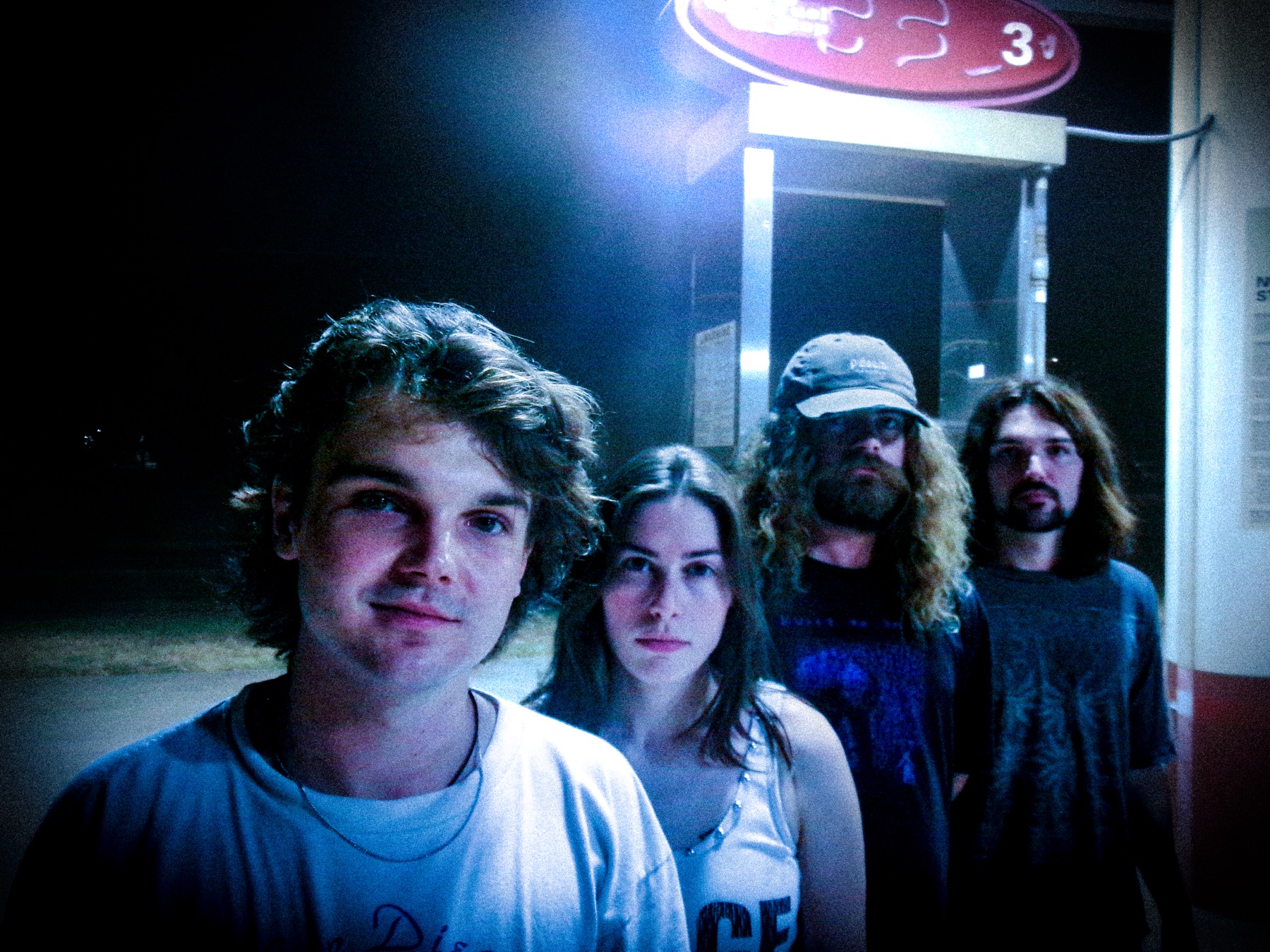 Judge Roy Scream band portrait at night, lit by a gas station sign